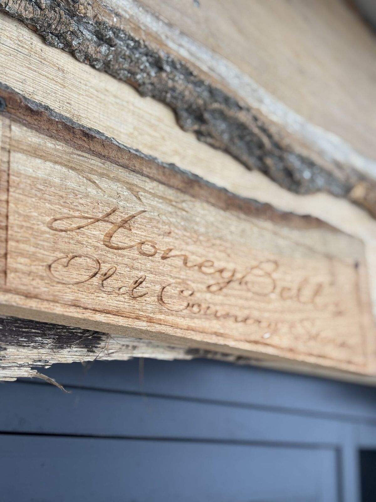 Hand-carved wooden sign reading HoneyBell's Old Country Store